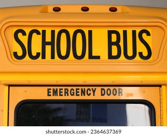 A closeup shot of the traditional yellow lettering for school bus with emergency door lettering from below - Shutterstock ID 2364637369