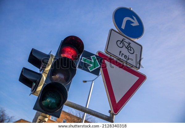 A close-up shot of\
traffic lights and road signs against a blue cloudy sky on a sunny\
day in Leipzig
