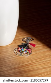 Close-up shot of a Tree of Life keychain decorated with colored stones, tassels and an owl pendant. The metal keychain is isolated on a wooden background. Top view.