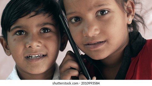 A Closeup Shot Of Two South Asian Children Speaking On The Phone Together