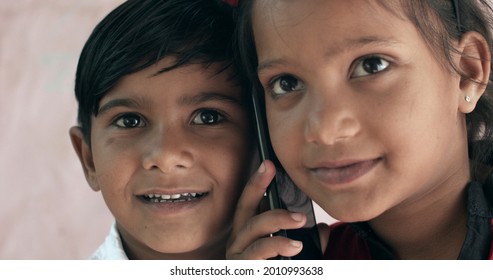 A Closeup Shot Of Two South Asian Children Speaking On The Phone Together