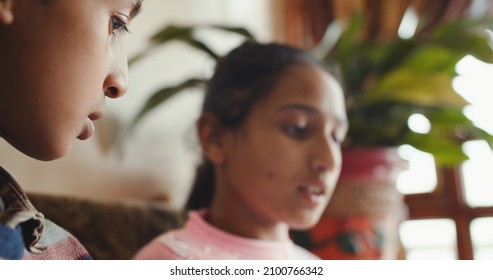 A Close-up Shot Of Two South Asian Kids Sitting Together In Front Of A Tablet