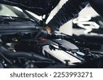 Close-up shot of unrecognisable man wearing black glove inspecting car engine and interior of hood of car. Garage work. Horizontal indoor shot. High quality photo