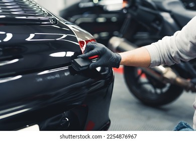 Close-up shot of unrecognisable man wearing black gloves applying ceramic coating to car using sponge. Professional car detailing. Horizontal indoor shot. High quality photo - Shutterstock ID 2254876967