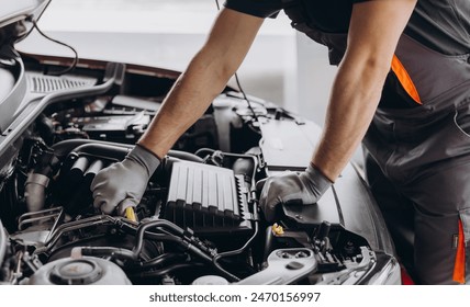 Close-up shot of unrecognisable man wearing gray glove inspecting car engine and interior of hood of car - Powered by Shutterstock