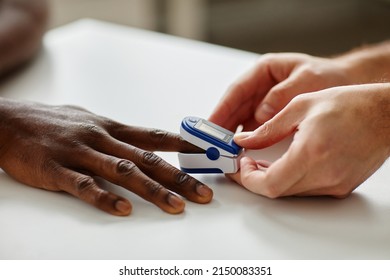 Close-up shot of unrecognizable doctor applying pulse oximeter on Black patients finger during appointment