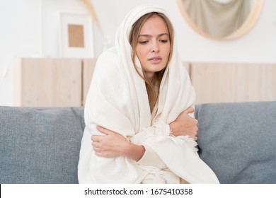 Close-up Shot Of Upset Young Woman Freezing, Feeling Cold At Home, Sitting On Sofa Covered With Blanket 