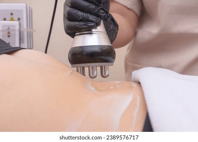 Closeup shot of using an RF electromagnetic device for radiofrequency abdomen tightening or waist slimming treatment. At a skin care, dermatologist or aesthetic clinic.