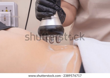 Closeup shot of using an RF electromagnetic device for radiofrequency abdomen tightening or waist slimming treatment. At a skin care, dermatologist or aesthetic clinic.