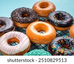 A close-up shot of a variety of donuts on a cooling rack. The donuts are topped with colorful sprinkles, pink stripes, and coconut flakes, with a focus on the front donut