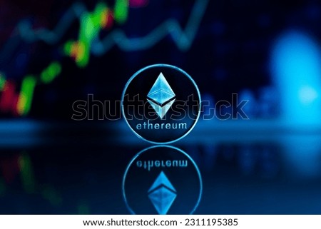 A closeup shot of a vertically positioned Ethereum coin in the blurry background of stock images