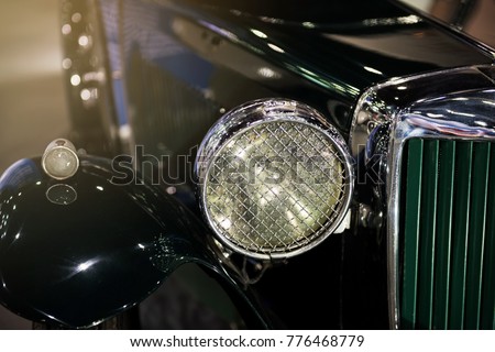 Closeup shot of vintage luxury green car front headlight. Antique vehicle decorating hobby for rich guy.