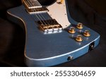 A close-up shot of a well used looking blue Theta guitar resting on a black cloth.