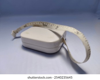 A close-up shot of a white retractable measuring tape displayed on a soft blue background, highlighting simplicity and precision. Ideal for themes of measurement, accuracy, and home improvement. - Powered by Shutterstock