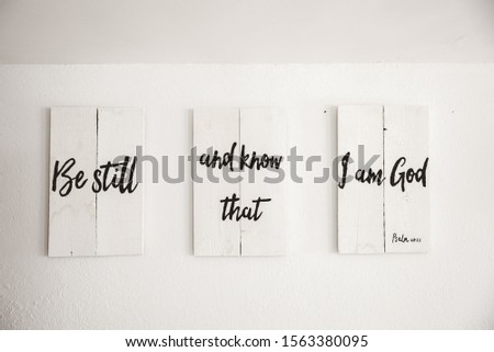 A closeup shot of white wooden sign with a bible quote written on it and a white background