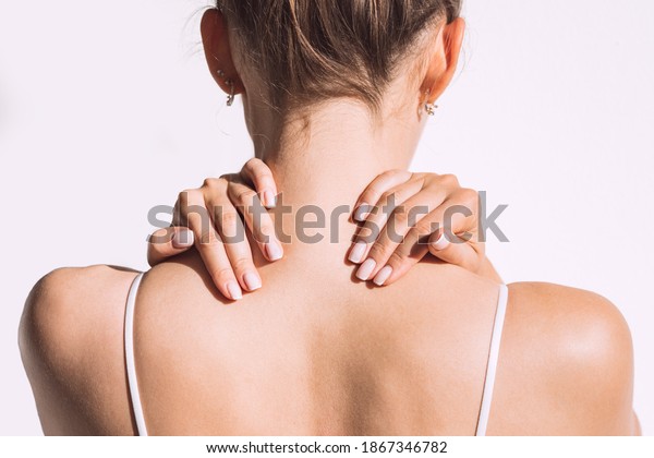 Closeup shot of woman\
from back having neck or shoulder pain. Injury or muscle spasm.\
Back and spine disease. Female massaging her neck. Health care and\
medical concept