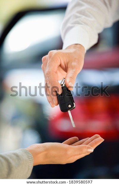 Close-up shot of woman at the car\
dealership getting the keys to her new car from the\
salesman.