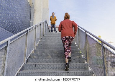 A closeup shot of a woman climbing stairs and a man giving instructions to her