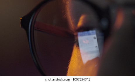 Close-up Shot Of Woman Eyes In Glasses Reflecting A Working Computer Blue Screen. Reflection Of Screen Of Tablet On Woman's Eyes With Glasses Macro View