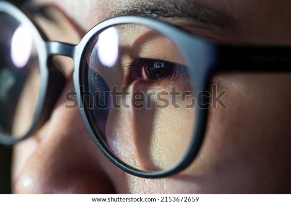Close-up shot of woman eyes in glasses reflecting\
a working computer blue\
screen
