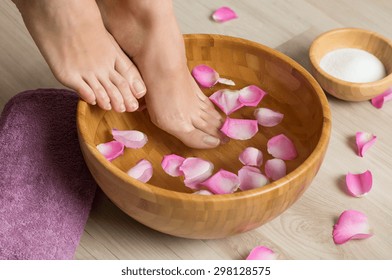 Closeup shot of a woman feet dipped in water with petals in a wooden bowl. Beautiful female feet at spa salon on pedicure procedure. Shallow depth of field with focus on feet.
 - Powered by Shutterstock