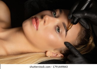Closeup shot of woman in gloves making permanent brow makeup to a young blonde woman in cosmetology salon - Shutterstock ID 1791449843