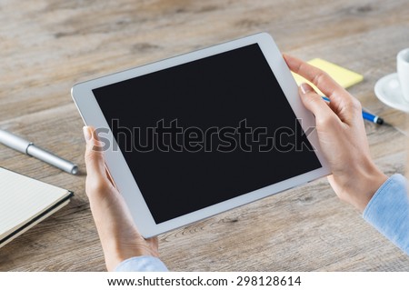 Closeup shot of a woman hand holding digitaltablet. Business woman showing a digital tablet with black screen in her office. Blank screen to put it on your own web page design.
