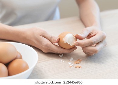 Close-up shot of woman hands peeling shell of boiled egg on the table. - Powered by Shutterstock