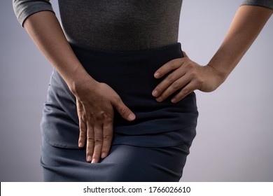 Closeup  shot of woman having painful holding hands pressing her crotch lower abdomen isolated on background