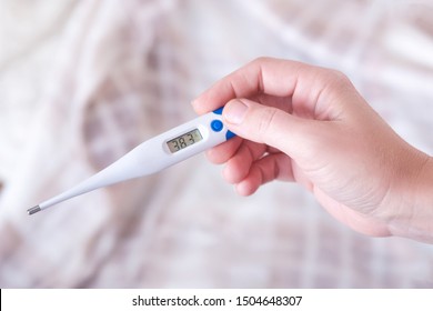 Closeup shot of a woman looking at thermometer. Female hands holding a digital thermometer. Girl measures the temperature. Shallow depth of field with focus on thermometer. - Shutterstock ID 1504648307