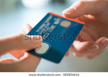 Closeup shot of a woman passing a payment credit card to the seller. Girl holding a credit card. Shallow depth of field with focus on the credit card.