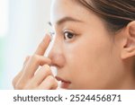 Close-up shot of woman putting contact lens in her eyes