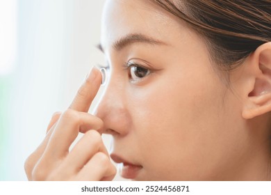 Close-up shot of woman putting contact lens in her eyes - Powered by Shutterstock