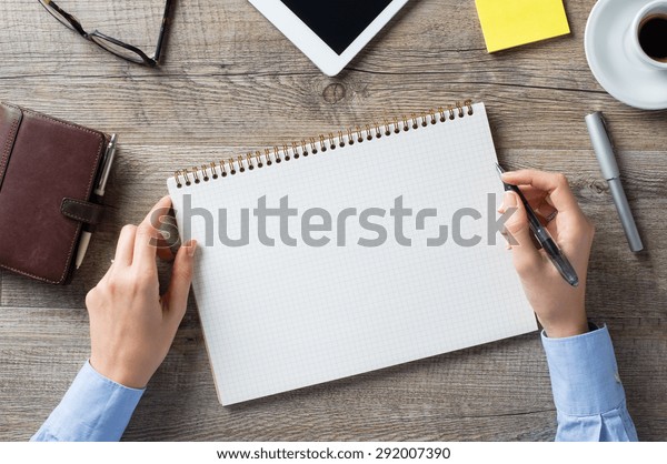 Closeup shot of a woman taking down note in a personal organizer. Business woman is writing in a diary in her office. Blank page to write it on your own message.