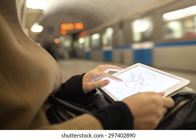 Close-up Shot Of Woman Using Touch Pad For Searching On Metro Map Being In Underground. Blurred Train In Background