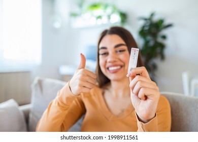 Close-up shot of woman's hand holding a negative test device. Happy young woman showing her negative Coronavirus - Covid-19 rapid test. Focus is on the test.Coronavirus - Shutterstock ID 1998911561