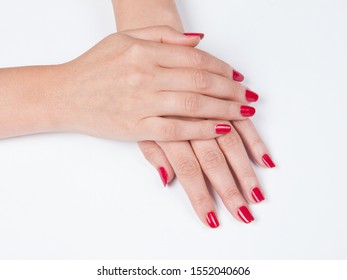 Closeup shot of woman`s hands with red manicure on a white background