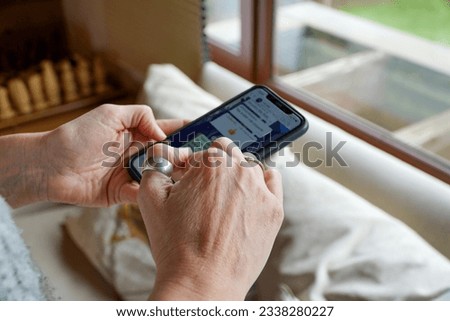 A close-up shot of a woman's hands typing on her phone inside her home, highlighting the details of modern communication.