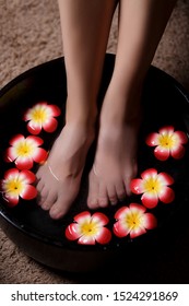 Close-up Shot Of A Woman's Leg Submerged In Water With Petals In A Bowl. Beautiful Women's Legs In The Spa On The Procedure Of Thai Massage