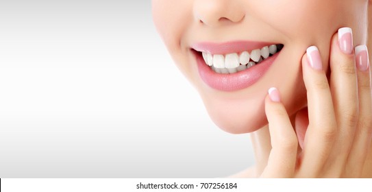 Closeup shot of woman's toothy smile against a grey background with copyspace