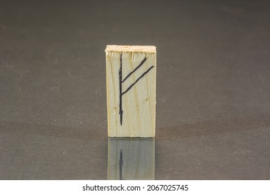 close-up shot of a wooden piece with a Norse rune engraved on it, specifically the fehu character