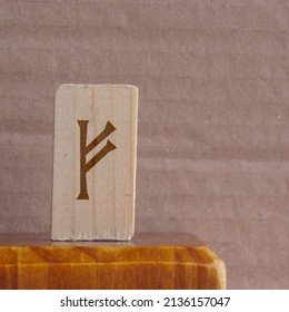 close-up shot of a wooden piece with a Norse rune engraved on it, specifically the fehu character