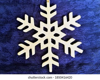 A Closeup Shot Of A Wooden Snowflake Ornament On A Blue Surface