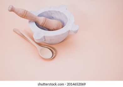 A closeup shot of wooden spoons beside mortar and pestle isolated on a pink background with copyscape