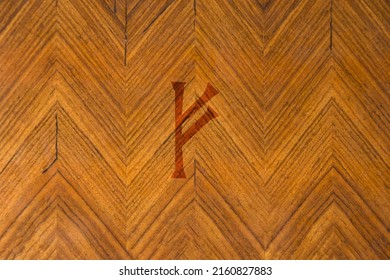 Close-up shot of a wooden surface with a Norse rune engraved on it, especially the Fehu character