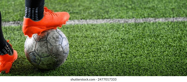 Close-up shot of a worn soccer ball with orange cleats on a grass field. - Powered by Shutterstock