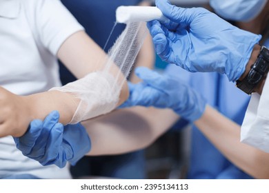 Close-up shot of a wound on the arm of a patient being carefully covered with a sterile dressing by multicultural medical professionals. Selective focus on a child being treated by a doctor and a - Shutterstock ID 2395134113