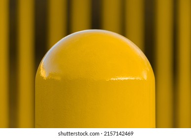 A closeup shot of a yellow pole or bollard on the street on a blurred background