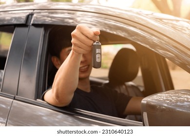 Close-up shot of young Asian man sitting in a car and handing out the car keys. - Powered by Shutterstock