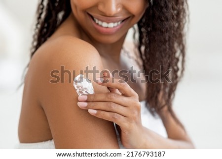 Closeup Shot Of Young Black Female Rubbing Moisturising Lotion To Skin, Unrecognizable Smiling African American Woman Applying Nourishing Cream on Shoulder, Enjoying Body Care, Cropped Image